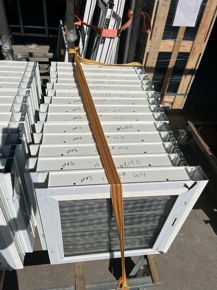 Completed white-framed window units grouped on the factory floor for the St. Lucia order
